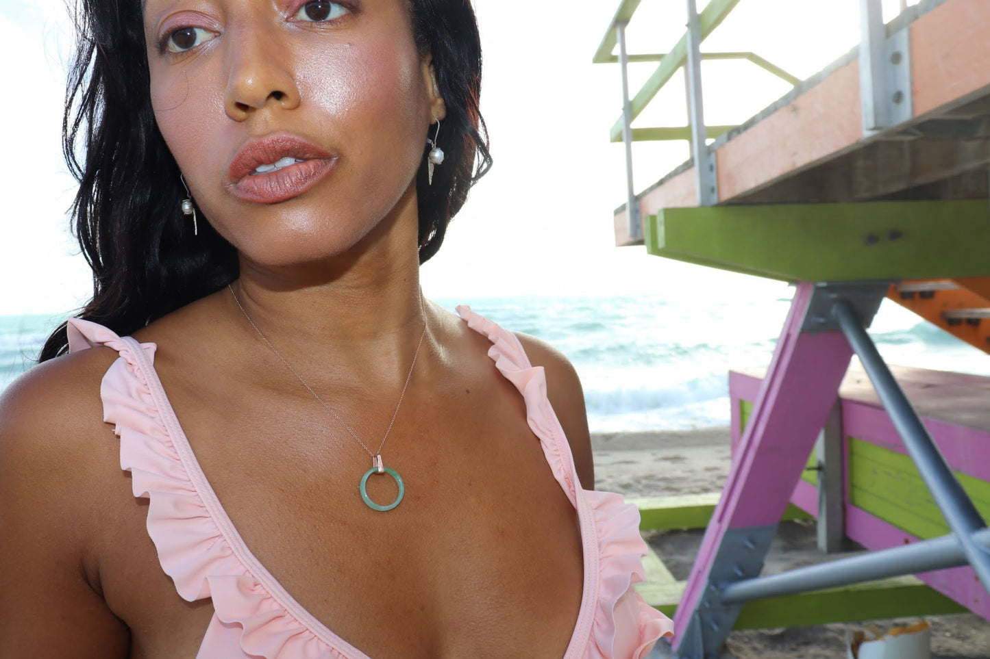 black woman in beach in pink bikini wearing the 18K Solid Rose Gold green jade ring on rose gold necklace from the wandering jewel