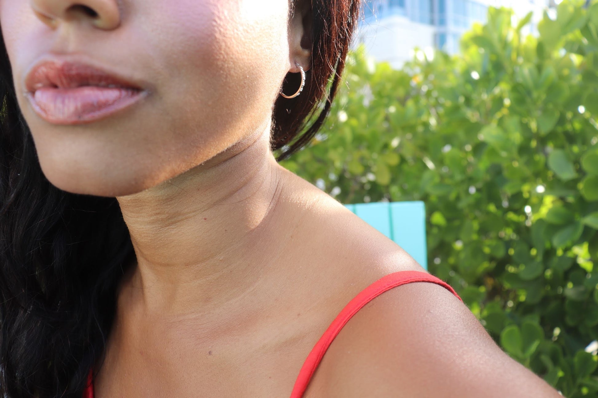 close up photo of a black woman sitting in garden in bright orange dress and wearing the 7 diamond cocktail earrings from the wandering jewel