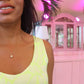 black woman in a neon yellow dress standing in a pink room  and wearing a the golden South sea pearl pendant necklace from the wandering jewel