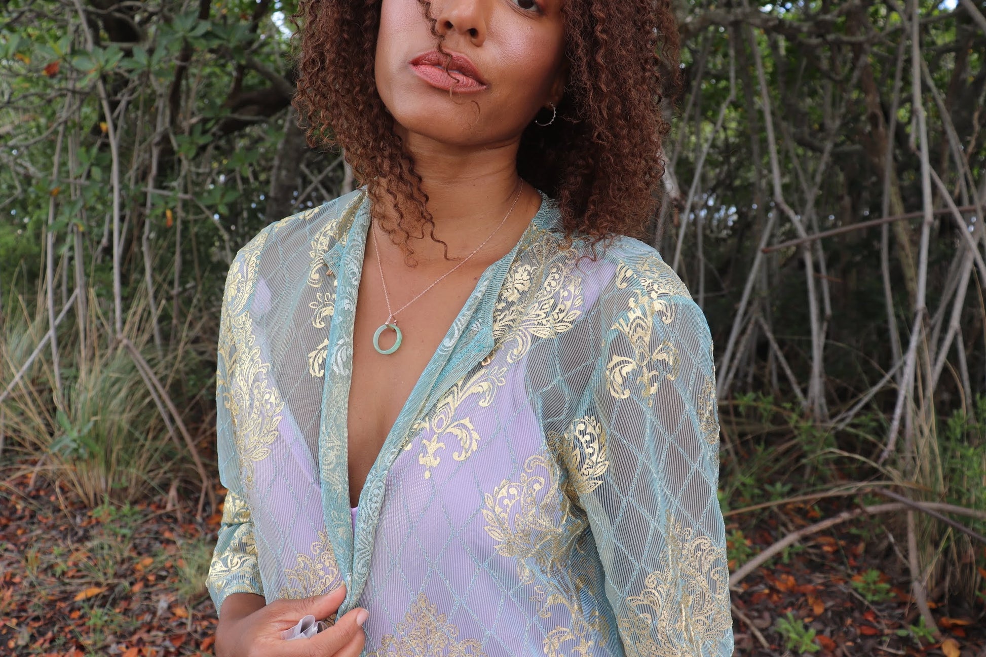 black woman in aqua in forest wearing the 18K Solid Rose Gold green jade ring on rose gold necklace from the wandering jewel
