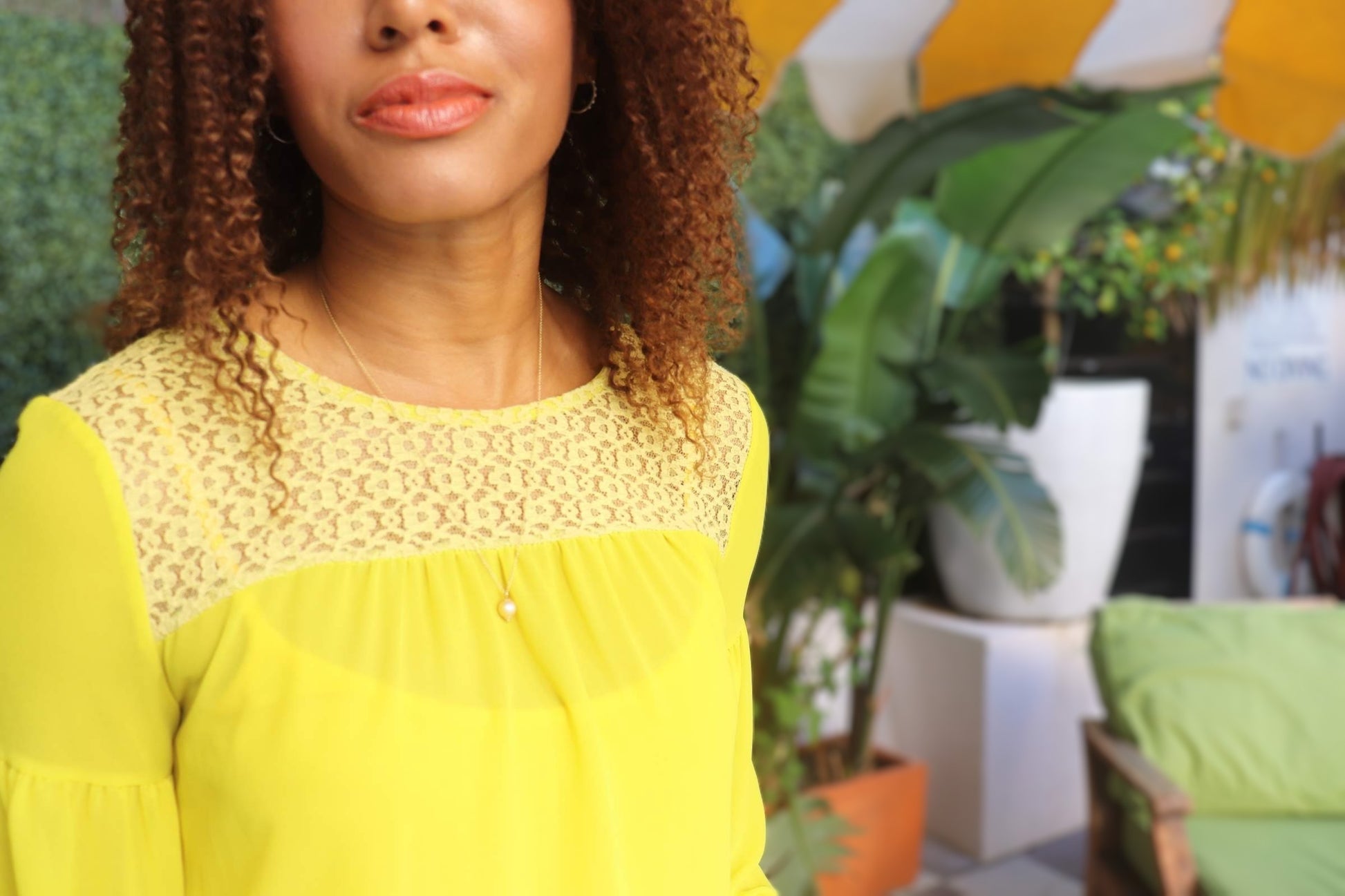 woman in yellow dress with curly hair wearing the golden South sea pendant from the wandering jewel