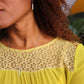 woman in yellow dress with curly hair wearing the 7 diamond pillar earrings and matching necklace from the wandering jewel