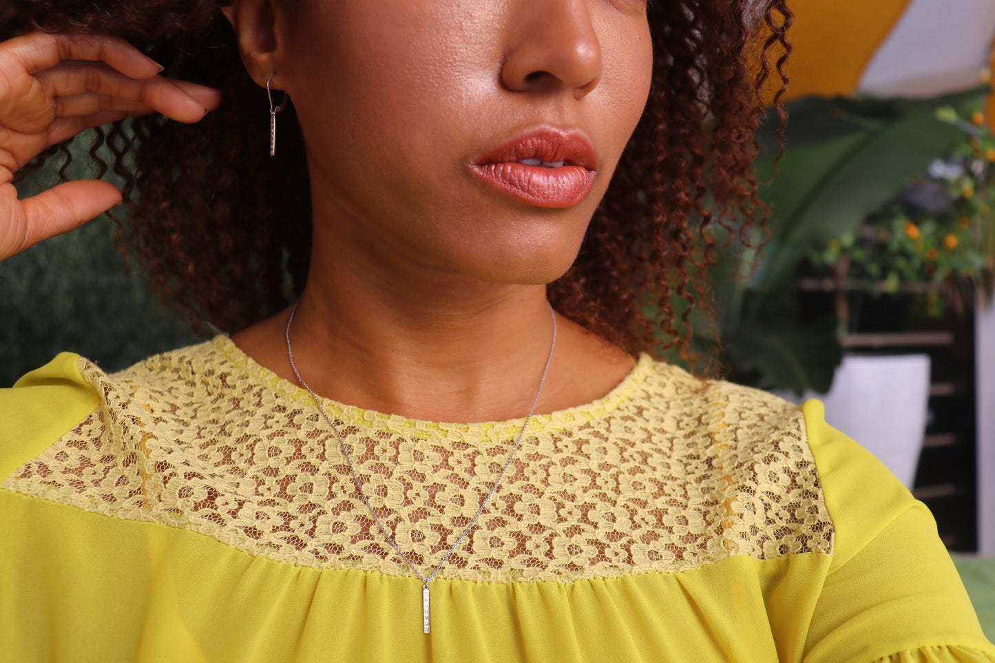 woman in yellow dress with curly hair wearing the 7 diamond pillar earrings and matching necklace from the wandering jewel