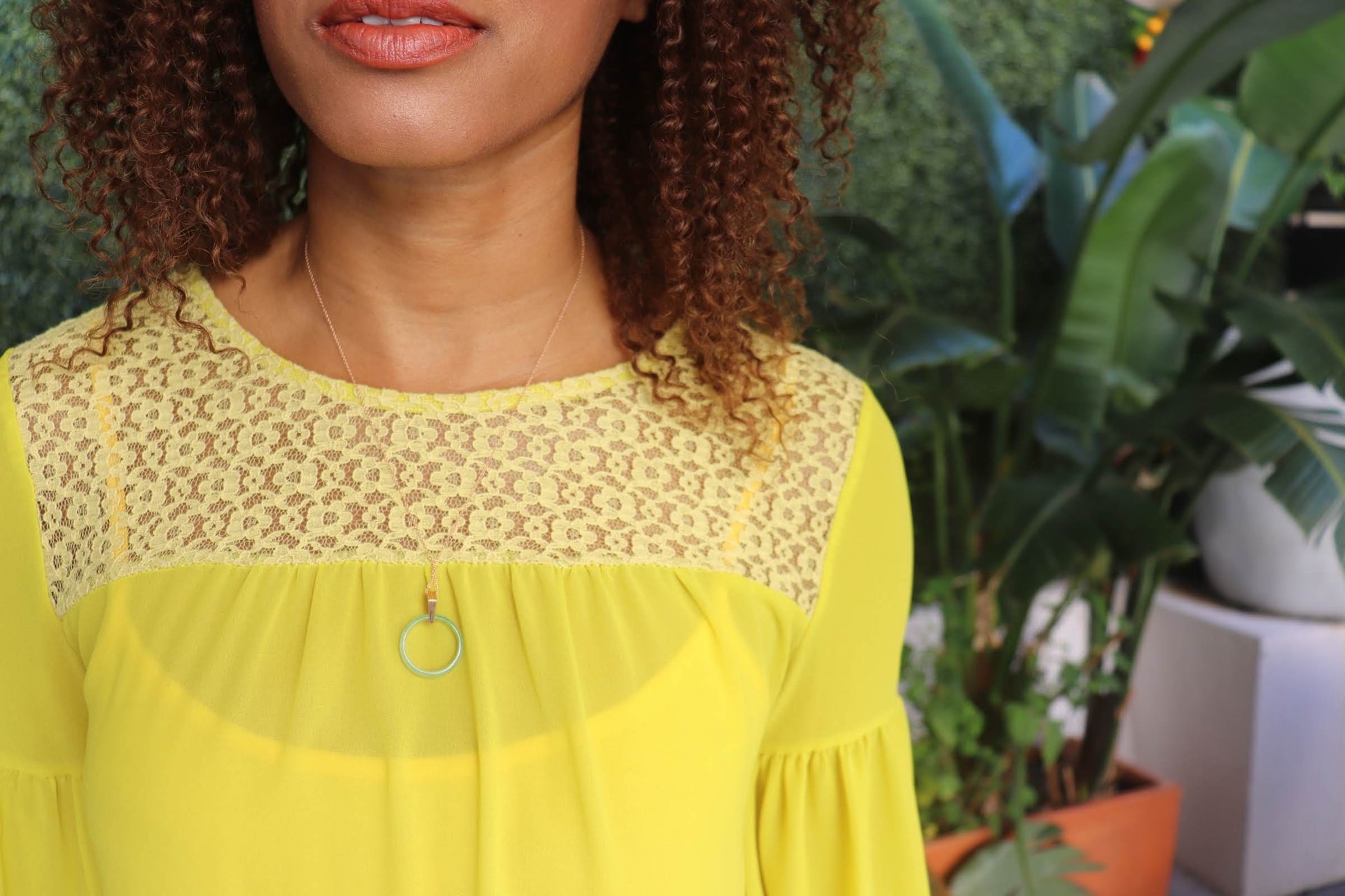 black woman in yellow dress at pool wearing the 18K Solid Rose Gold green jade ring on rose gold necklace from the wandering jewel