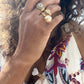 Black woman in floral dress with long hair wearing the Gold 8 sided octagon ring with an eight ball inscribed in black diamonds from the wandering jewel