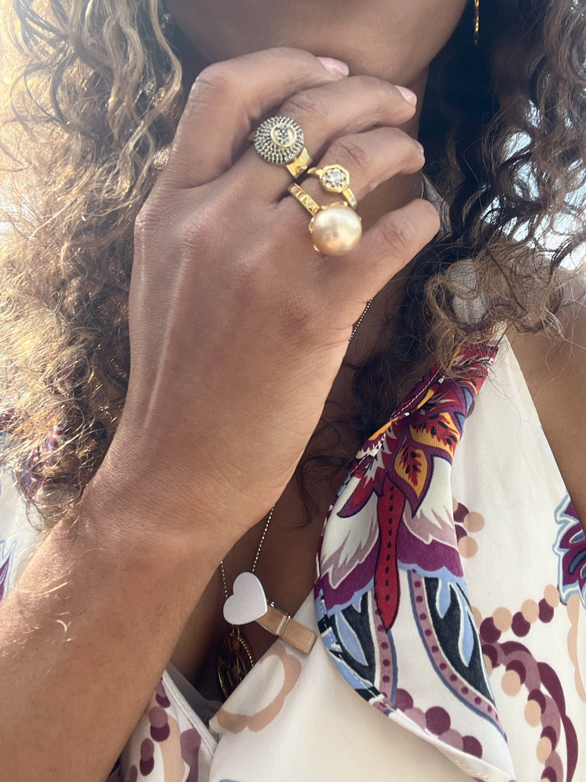 Black woman in floral dress with long hair wearing the Gold 8 sided octagon ring with an eight ball inscribed in black diamonds from the wandering jewel
