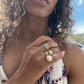 Black woman in floral dress outside on beach wearing the infinity Gold 8 sided octagon ring with an eight ball inscribed in black diamonds from the wandering jewel