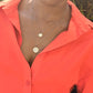 woman in an orange button up blouse wearing the wandering jewel's 7 diamond star of david pendant and coin necklaces