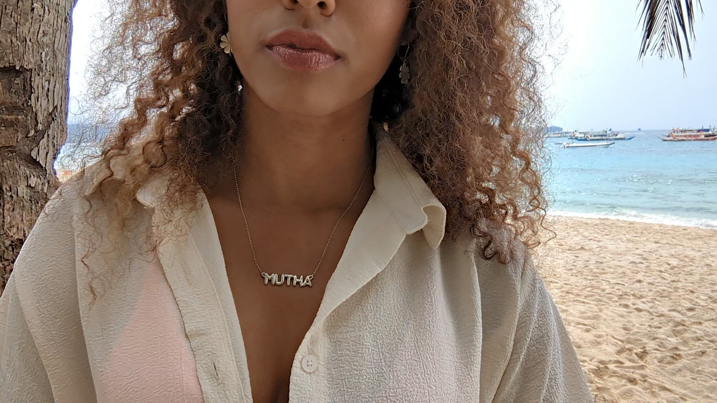 woman on beach in white blouse wearing the mutha mother necklace from the wandering jewel