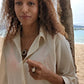 woman in beach in white blouse wearing the st Joseph hex nut ring from the wandering jewel