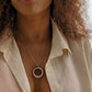woman wearing white cover up on beach wearing the white jade ring necklace pendant from the wandering jewel