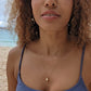 black woman with curly hair and purple bikini on beach wearing the golden South sea pearl pendant from the wandering jewel