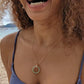 black woman in purple bikini on beach wearing the 18K Solid Rose Gold green jade ring on rose gold necklace from the wandering jewel