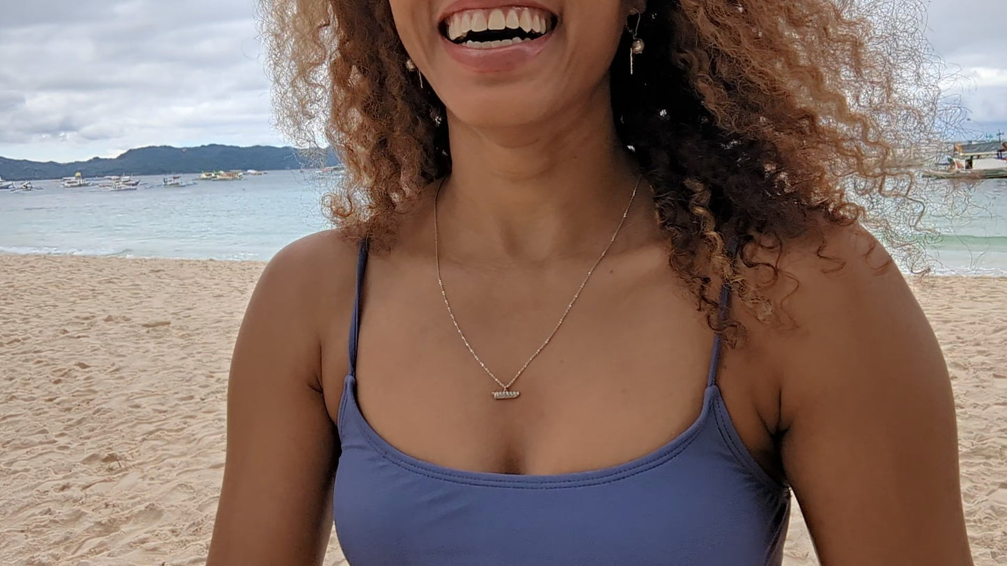black woman on a beach in purple bikini wearing  the 7 diamond heart pendant from the wandering jewel