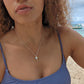 woman on beach in purple bikini wearing a silver palm tree necklace from the wandering jewel
