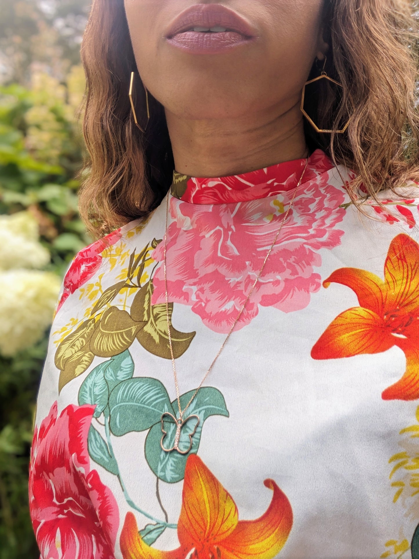 black woman in a multi color dress in garden wearing the 7 diamond butterfly necklace from The Wandering Jewel