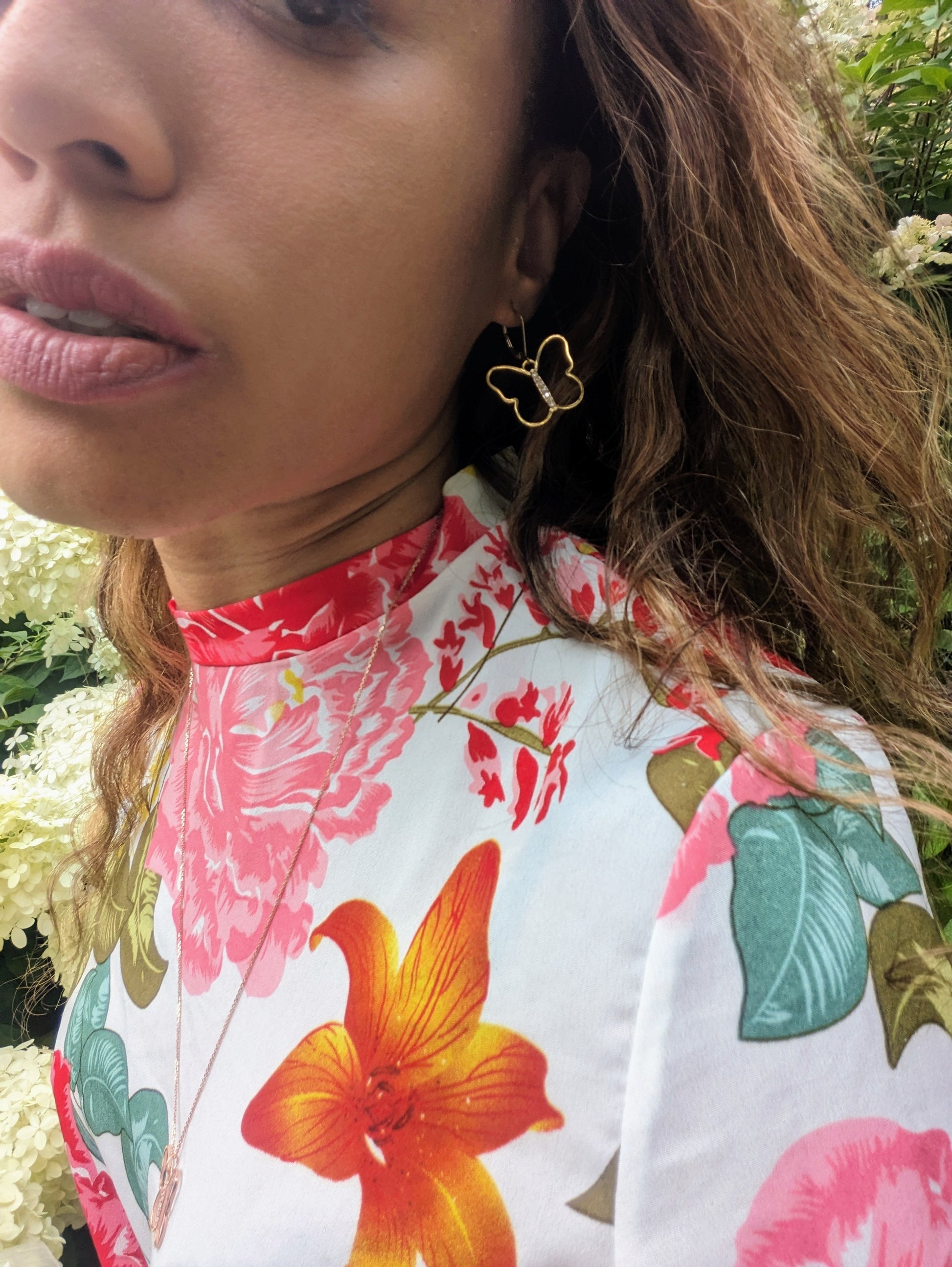 black woman in a multi color dress in garden wearing the 7 diamond butterfly earrings from The Wandering Jewel