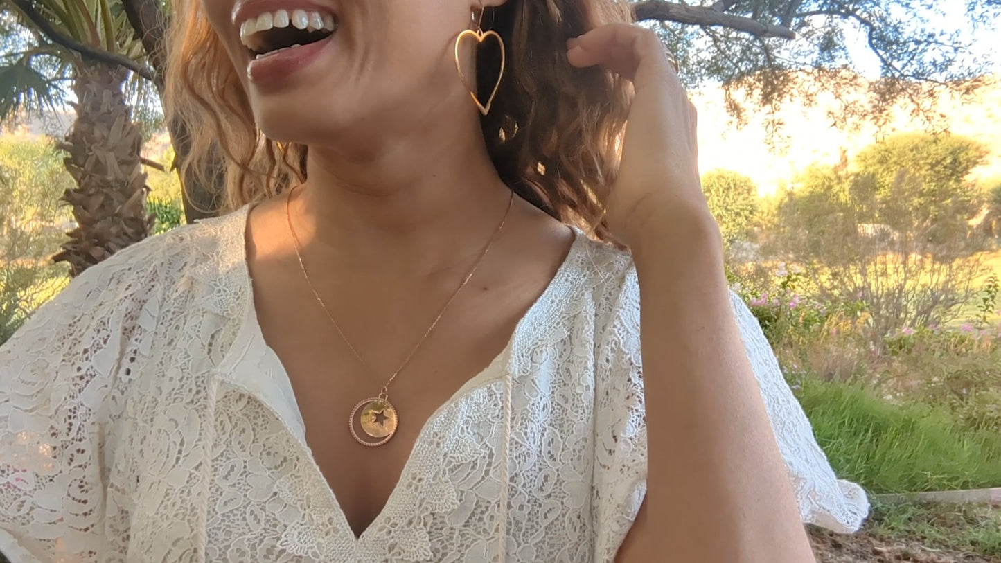 woman in white dress in a garden wearing the moon and Star cutout coin necklace from  the wandering jewel