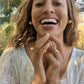 woman in white dress laughing in a garden and wearing multiple 7 diamond disengagement rings from the wandering jewel
