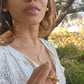  black woman in garden in a white dress wearing large gold South sea pearl diamond earring studs from the wandering jewel