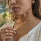 black woman in garden in a white dress wearing large gold South sea pearl diamond earring studs from the wandering jewel