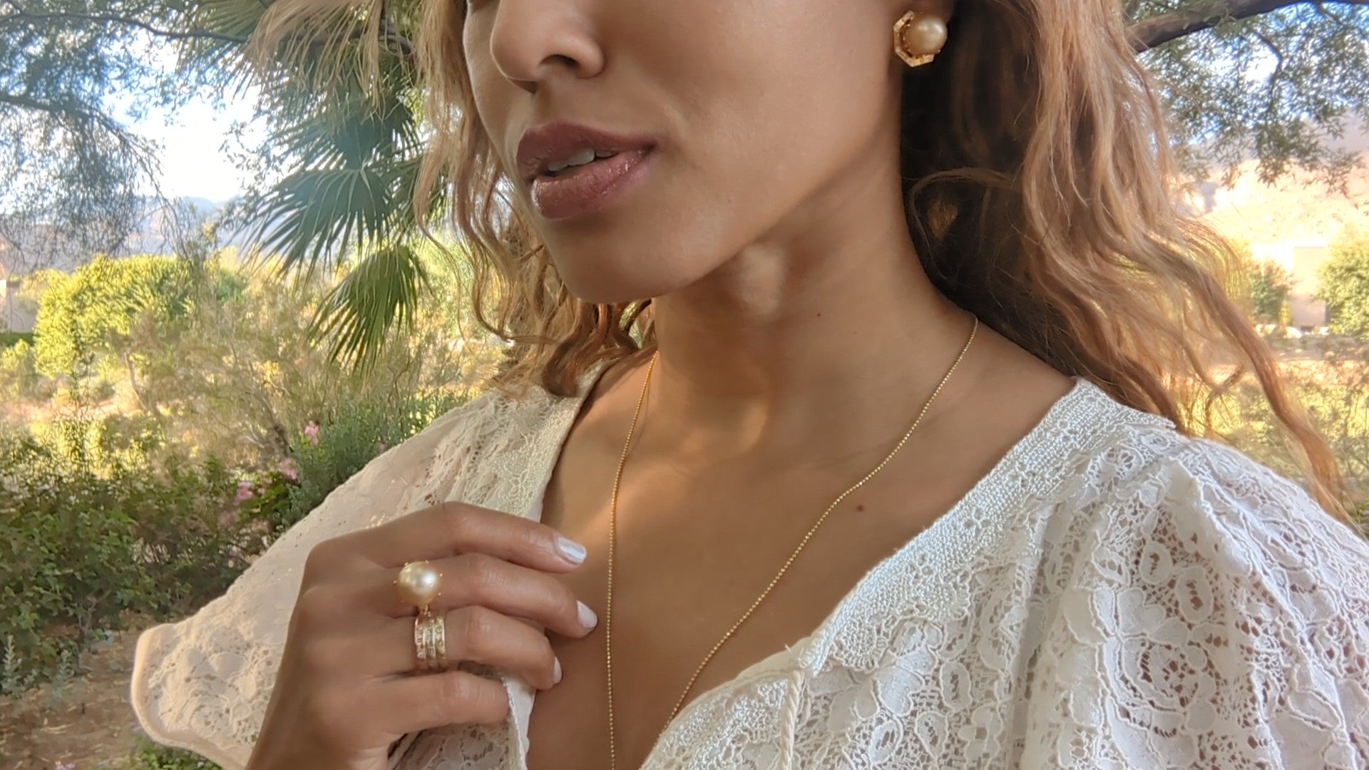 black woman in garden in a white dress wearing large gold South sea pearl diamond earring studs from the wandering jewel