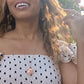 woman in polka dot dress in a street in Greece wearing a the moon and Star cutout coin necklace from the wandering jewel