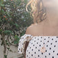 black woman in polka dot dress on a Greek island wearing the Rose gold star of David pendant necklace coin from the wandering jewel