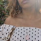 black woman wearing a polka dot dress on a European street and wearing the Rose gold star of David pendant necklace coin from the wandering jewel