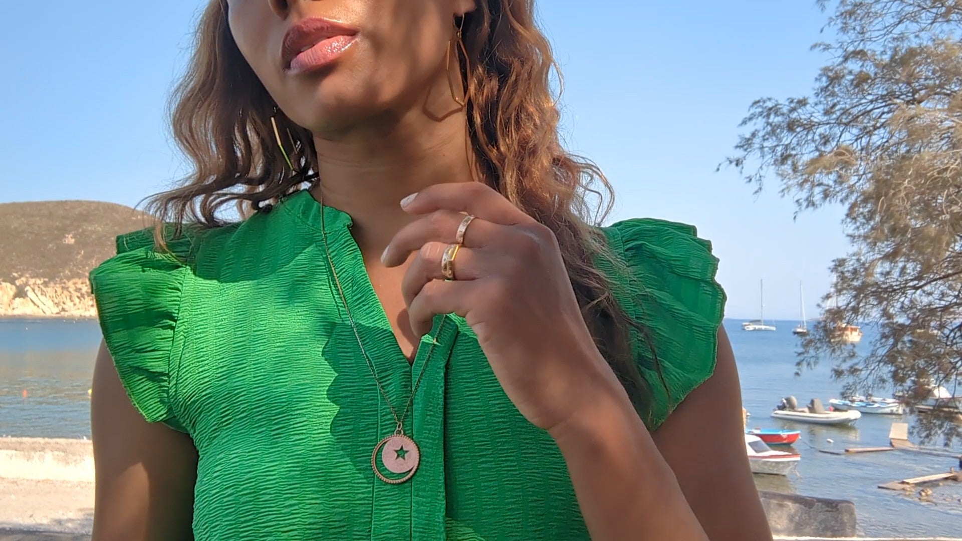 woman in green dress standing in the marina and wearing the moon and Star cut out coin necklace from the wandering jewel