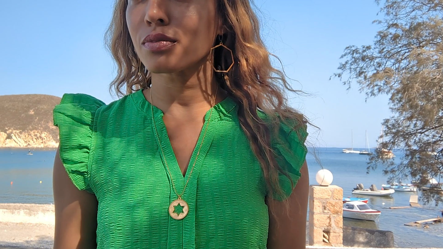black woman in green dress in marina wearing Rose gold star of David pendant necklace coin from the wandering jewel
