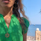 black woman on marina  in green dress wearing Large gold hoop diamond earrings septagon shaped from the wandering jewel