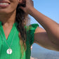 black women in harbor wearing a green dress and the cross coin cutout pendant from the wandering jewel