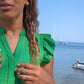 woman on marina in green dress wearing the gold septagon disengagement ring from the wandering jewel