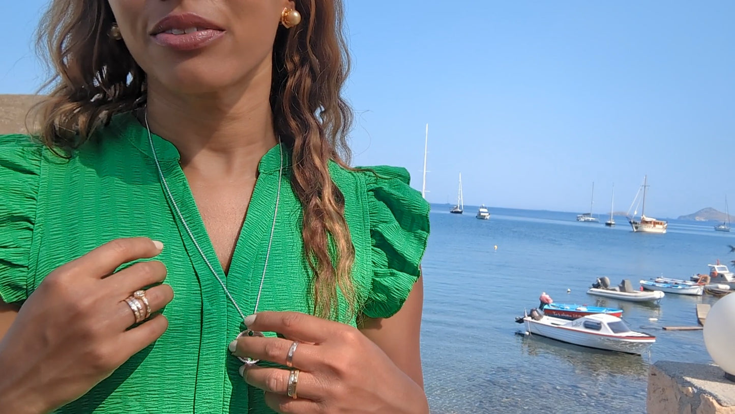 woman on marina in green dress wearing the gold septagon disengagement ring from the wandering jewel