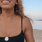  black woman on Greek beach in black bikini wearing large gold South sea pearl diamond earring studs from the wandering jewel