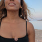 black woman in black bikini on Greek beach wearing the Rose gold star of David pendant necklace coin from the wandering jewel