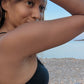 black woman in black bikini on Greek beach wearing the 7 diamond butterfly earrings from the wandering jewel