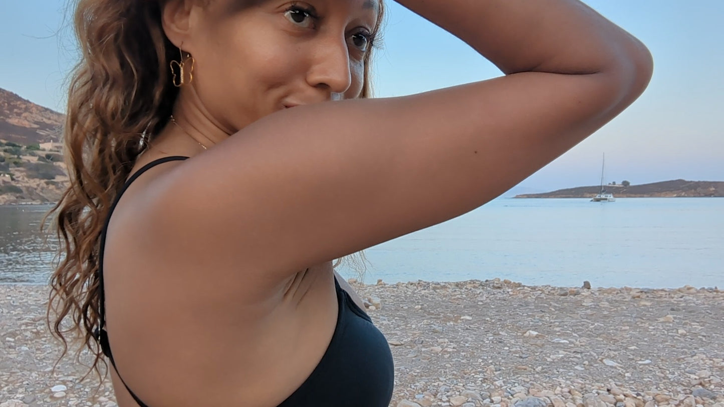 black woman in black bikini on Greek beach wearing the 7 diamond butterfly earrings from the wandering jewel