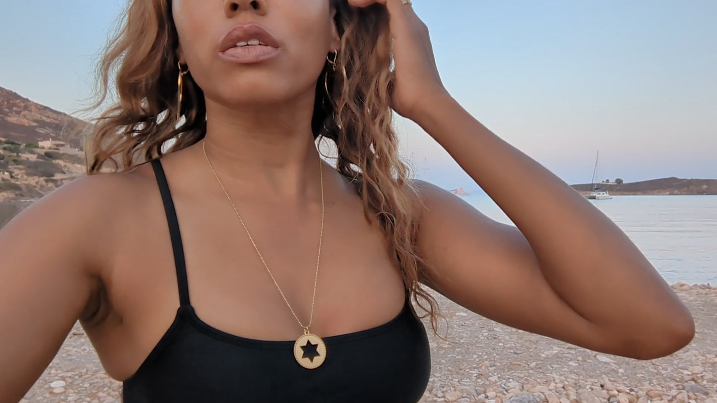 black woman  on beach wearing black bikini Rose gold star of David pendant necklace coin from the wandering jewel