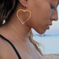 woman on beach in black bikini wearing a large hoop earrings shaped like a heart from the wandering jewel
