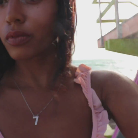 video of woman on beach in pink bikini wearing the 7 diamond number 7 necklace from the wandering jewel