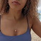 video of a black woman with curly hair and purple bikini on beach wearing the golden South sea pearl pendant from  the wandering jewel