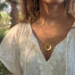 black woman in white dress in a garden wearing Rose gold star of David pendant necklace coin from the wandering jewel
