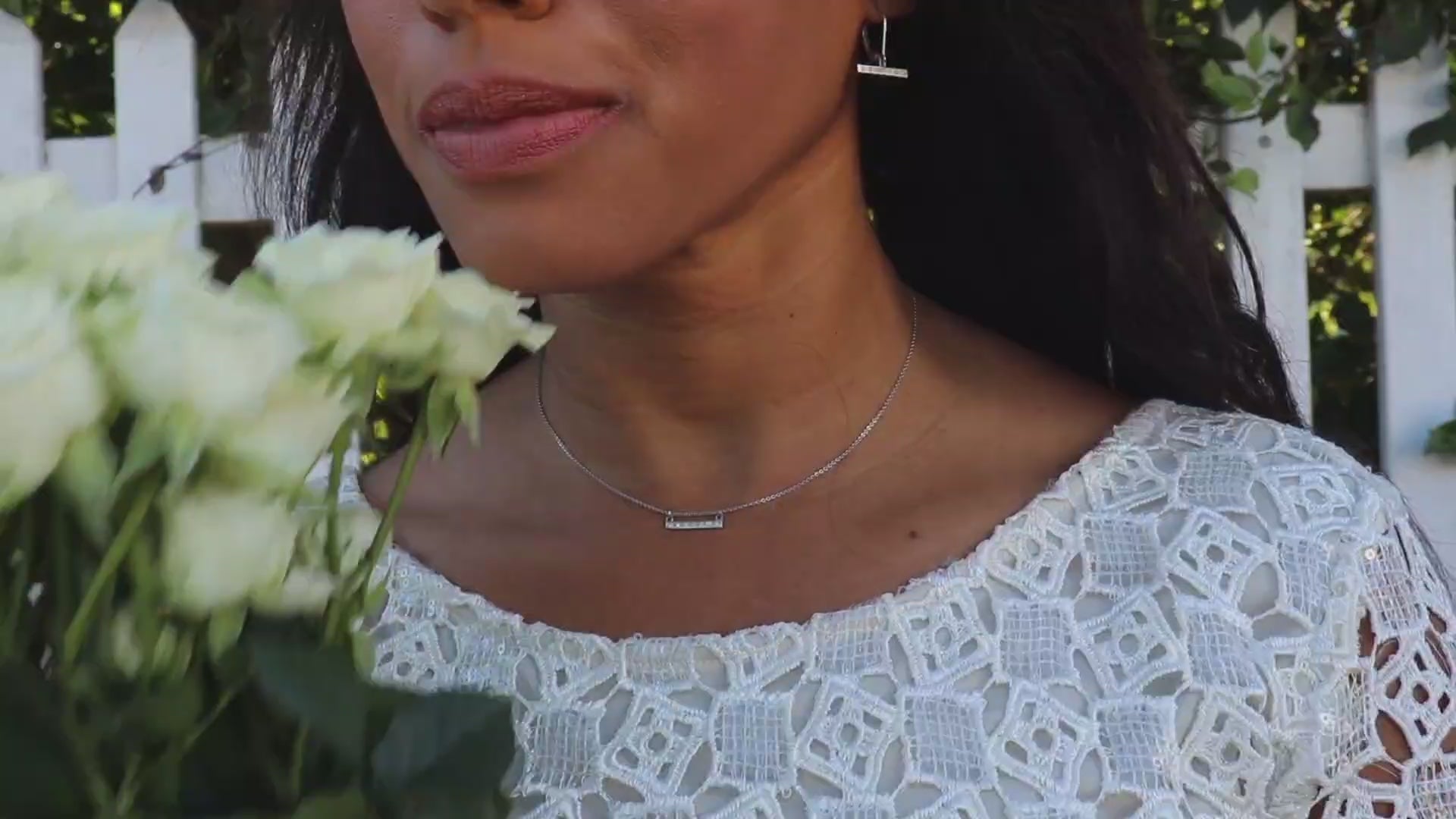 video of woman white dress in front of a picket fence wearing the 7 diamond horizon earrings from the wandering jewel