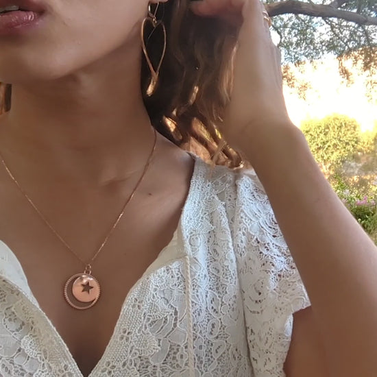 video of woman in white dress in a garden wearing the moon and Star cutout  coin necklace from the wandering jewel