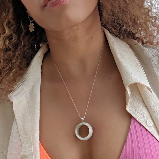 video of woman at beach in a white blouse and pink and orange bikini wearing a white jade necklace from the wandering jewel