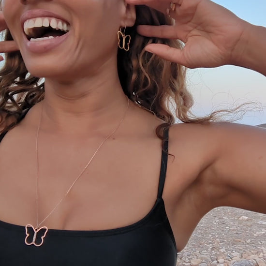 woman in black bikini  on beach wearing the 7 diamond butterfly earrings and necklace from the wandering jewel
