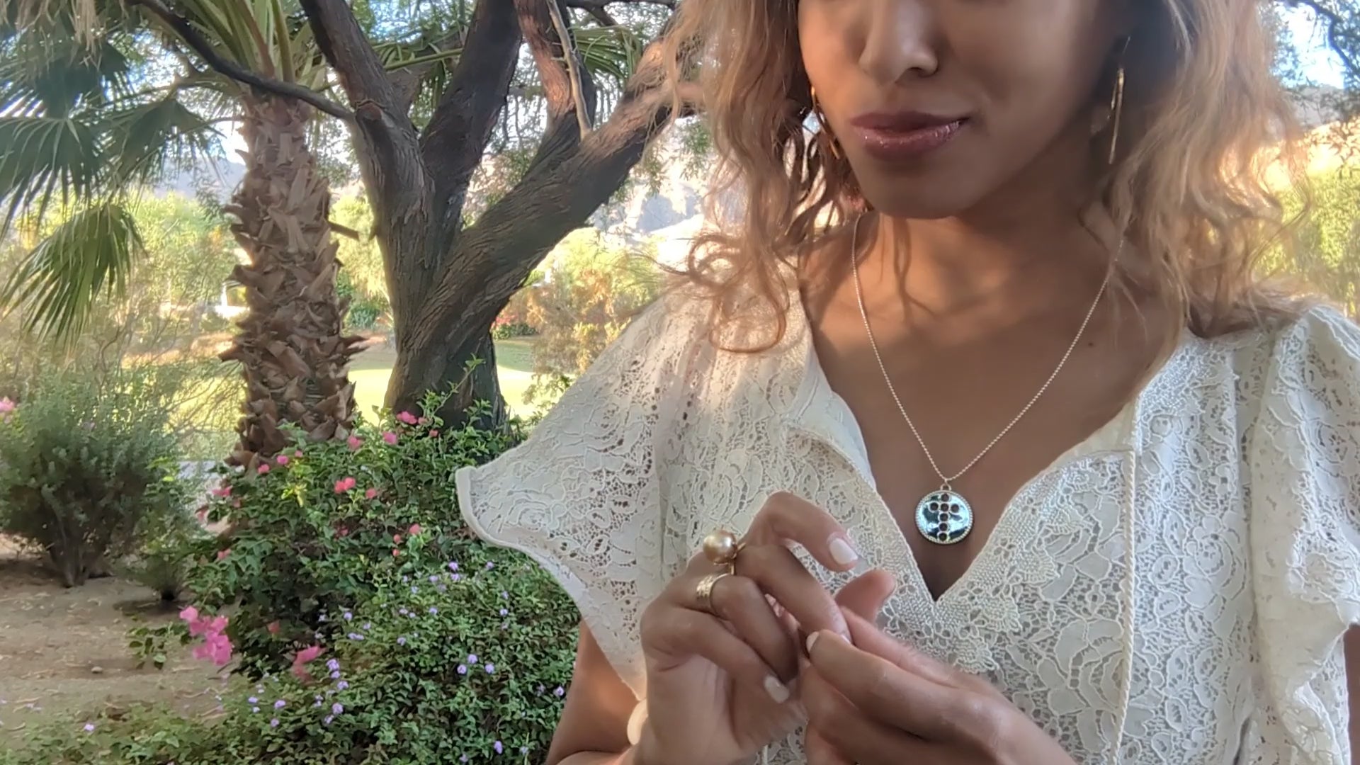 video of woman in white dress in garden wearing the silver cross cutout coin from the wandering jewel