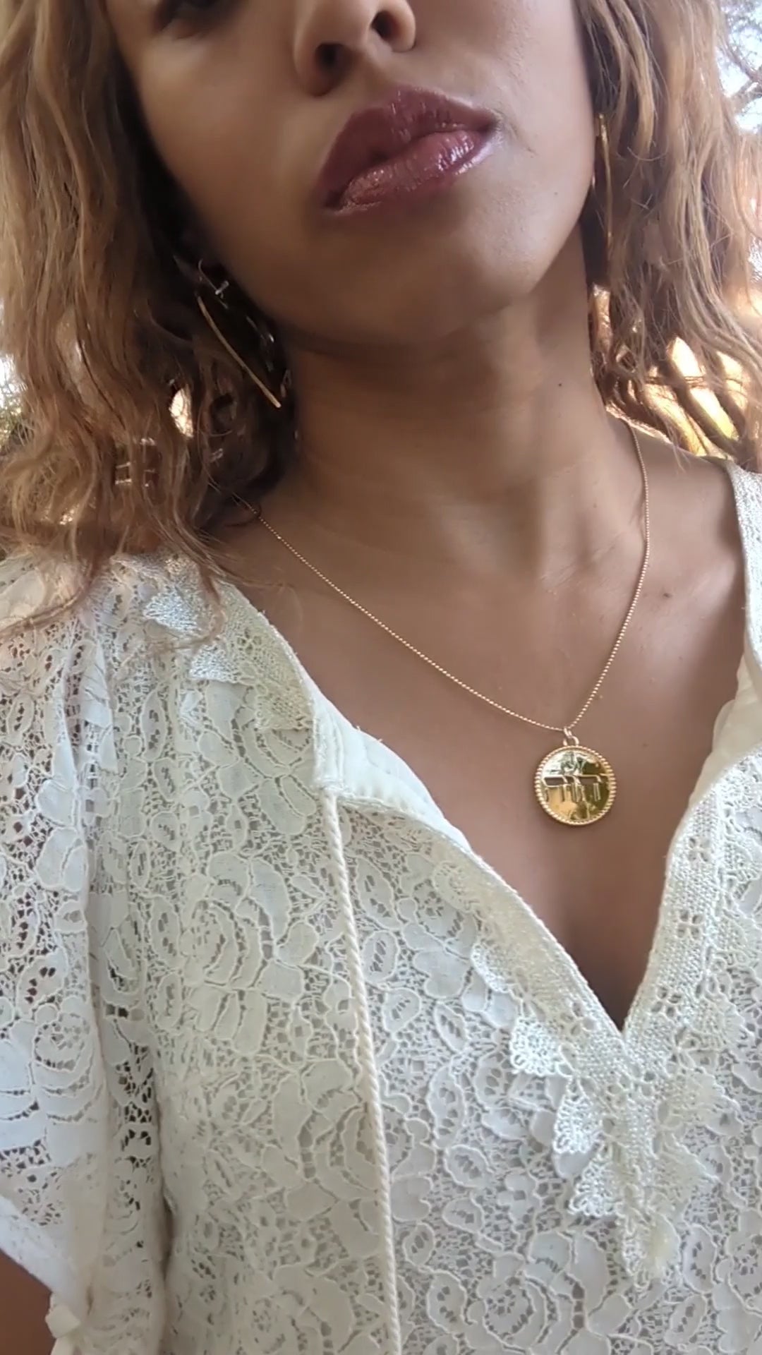 video of black woman in white dress in garden desert wearing the Jehovah cutout coin from the wandering jewel